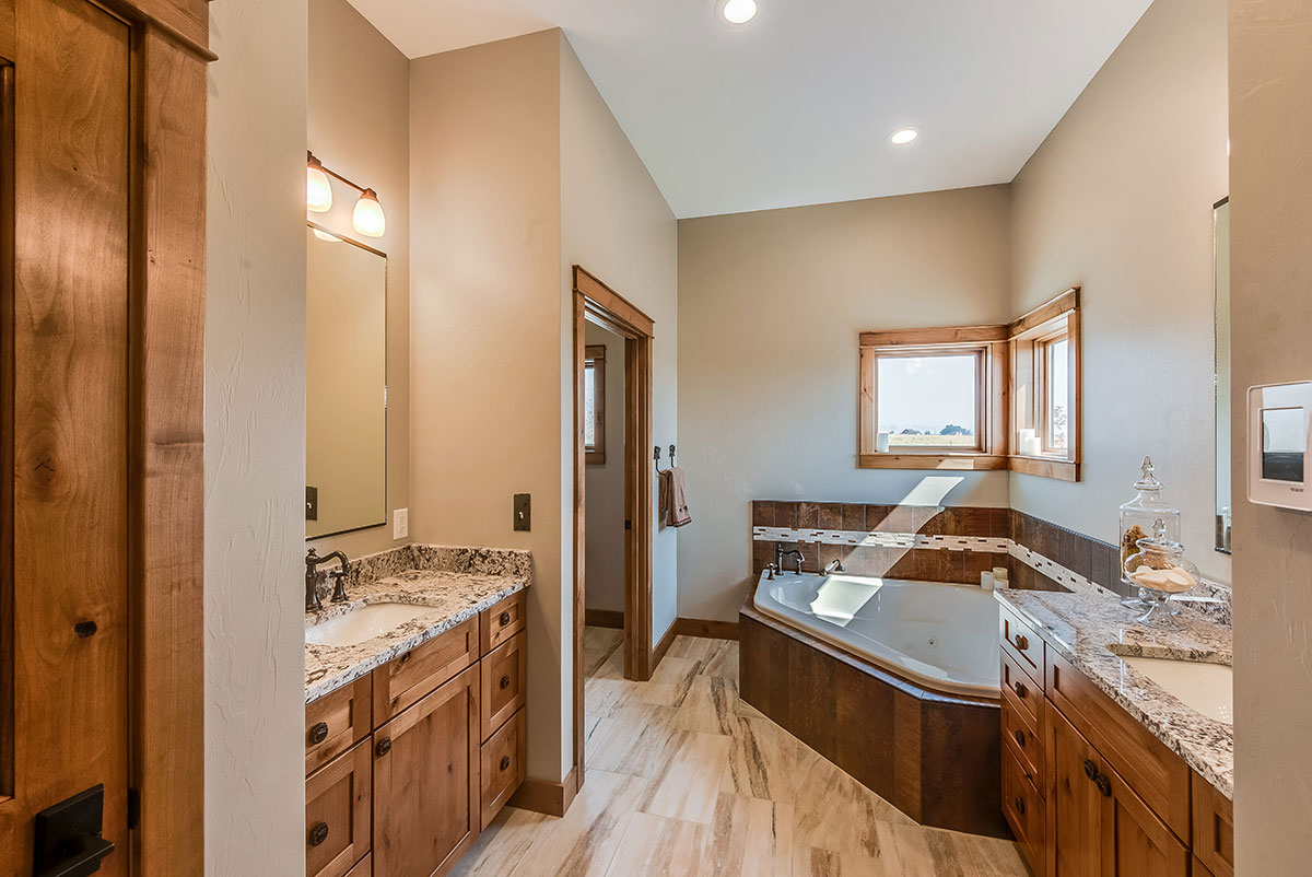 Natural light in bathroom with a single vanity on either side of the room with a large jacuzzi tub in the corner below window