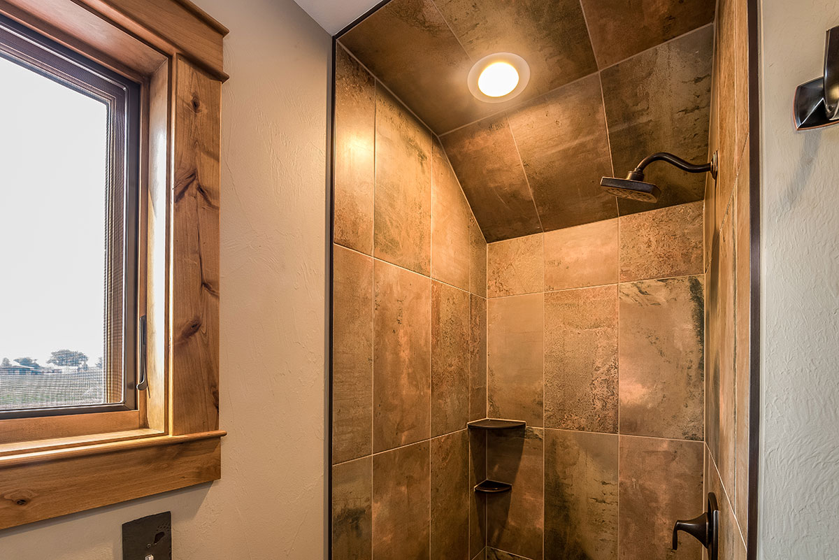 looking into a shower with tile backsplash and a warm light in the celiing above