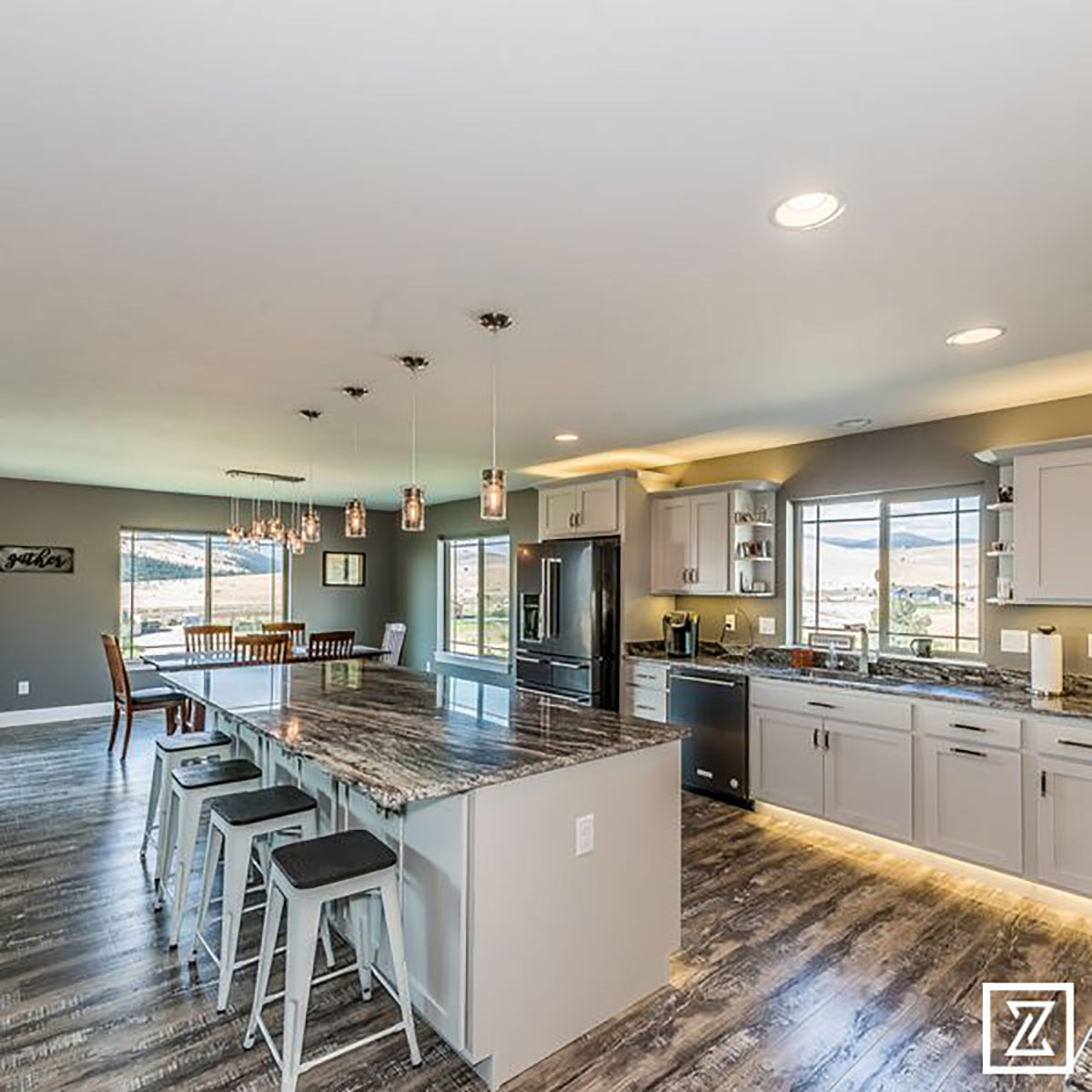 An open kitchen view facing the island bar with lots of light and windows with mountains in the distance