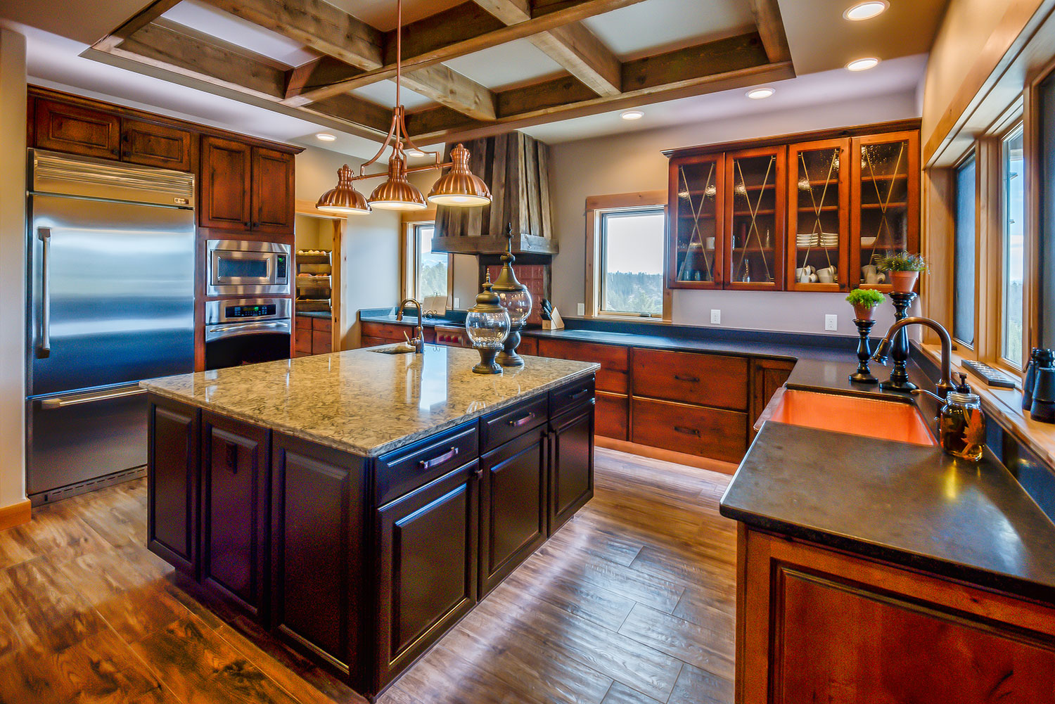 Rustic kitchen with granite countertops and copper farmhouse sink and exposed wood beams in ceiling