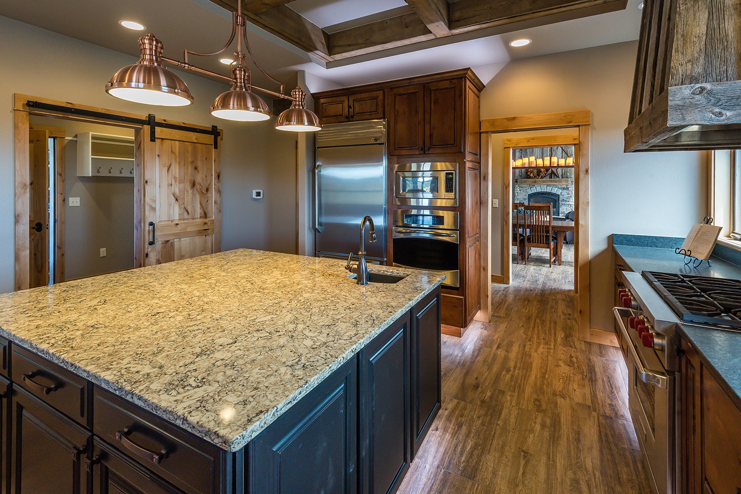 Kitchen with professional gas range below a rustic trimmed hood with appliances in wall next to a doorway to the dining room