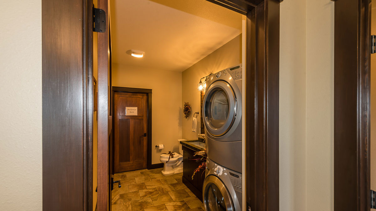 View of a guest bathroom with a toilet with a bow on it and a vanity and a stacking washer and dryer