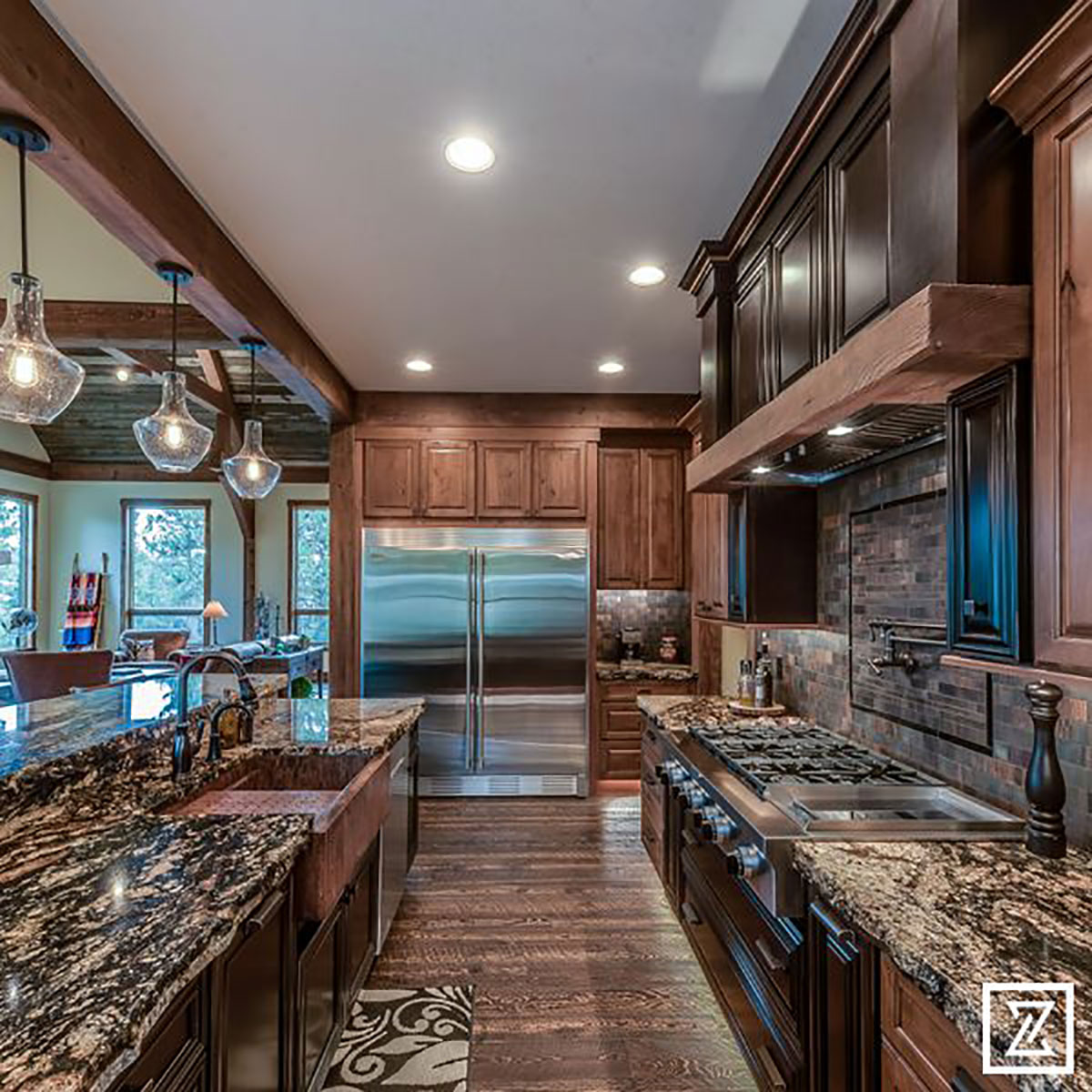 Central view of kitchen facing large french door refrigerator with island on the left and stove and backsplash to the right